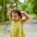 Adorable young girl playing in a lush green forest on a bright spring day.