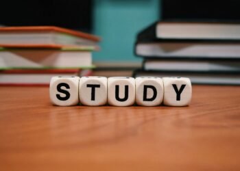 Close-up of study blocks and stacked books on a wooden desk, symbolizing education and learning.