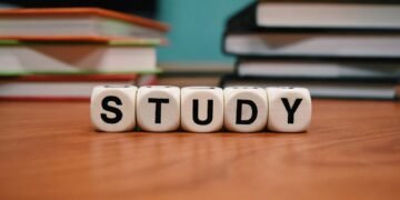 Close-up of study blocks and stacked books on a wooden desk, symbolizing education and learning.