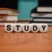 Close-up of study blocks and stacked books on a wooden desk, symbolizing education and learning.