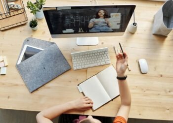 Teen girl actively learning in an organized home workspace via online class on a desktop computer.