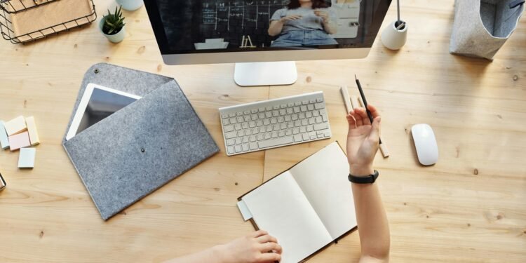 Teen girl actively learning in an organized home workspace via online class on a desktop computer.
